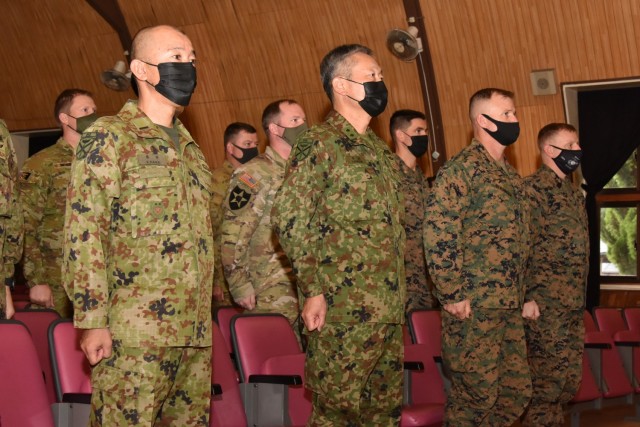 Japan Ground Self-Defense Force Maj. Gen. Takanori Hirata, commanding general of the Amphibious Rapid Deployment Brigade (ARDB), and U.S. Marine Corps Col. Charles Readinger, chief-of-staff for the 3rd Marine Expeditionary Brigade (MEB), stand at attention with Australian Defence Force observers from 1st Division, U.S. Army representatives of the 5th Security Force Assistance Brigade, and other members of the ARDB and 3rd MEB as the national anthems of participating countries are played at the opening ceremony of exercise Yama Sakura 81 aboard Camp Ainoura, Nagasaki, Japan, Dec. 5, 2021. Yama Sakura 81 is the largest U.S.-Japan bilateral and joint command post exercise which enables participants to work as dedicated partners in support of the Japan-U.S. security alliance and for continued peace and stability in the Indo-Pacific.