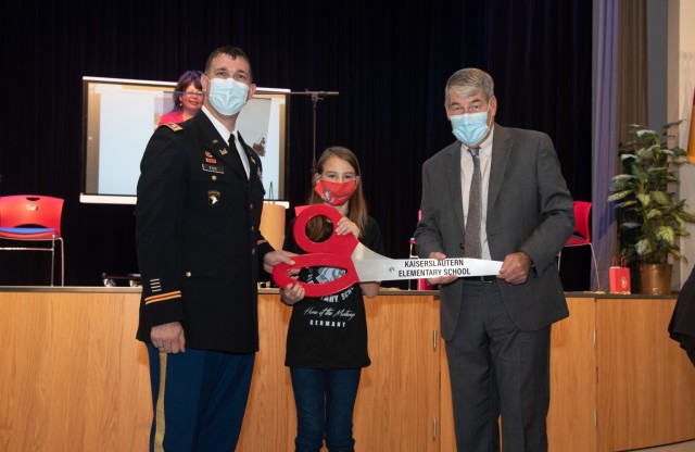 Lt. Col. Daniel J. Fox, deputy commander of the U.S. Army Corps of Engineers Europe District, a Kaiserslautern Elementary School student, and Thomas Brady, director of the Department of Defense Education Activity hold the ceremonial scissors...