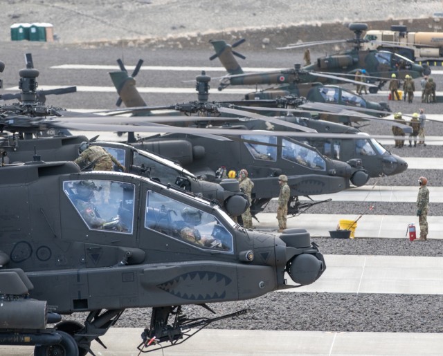 Helicopters assigned to 16th Combat Aviation Brigade, U.S. Army, and 1st Battle Helicopter Unit, Japanese Ground Self Defense Force, receive fuel and Hellfire missile armaments at Yakima Training Center, Wash., on Dec. 6, 2021.  The units are preparing to conduct a combined Hellfire shoot as part of Exercise Rising Thunder 21. (U.S. Army photo by Capt. Kyle Abraham, 16th Combat Aviation Brigade)