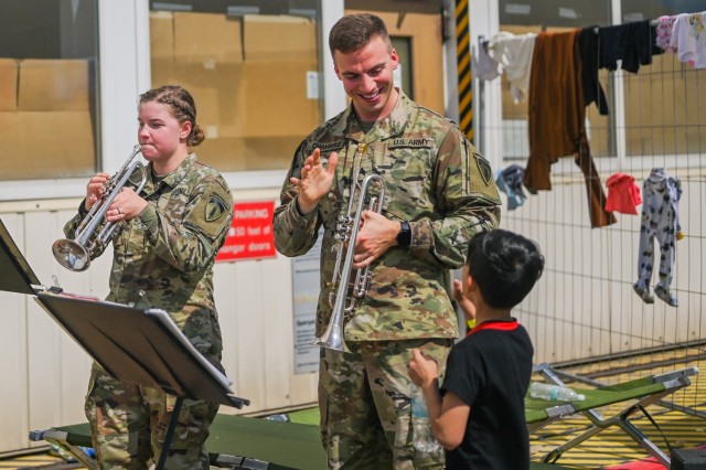 U.S. Army Sgt. Robert Chambers, U.S. Army Europe and Africa Band and Chorus musician waves at a child at Ramstein Air Base, Germany, Aug. 24, 2021. The USAEUR-AF Band & Chorus supported Operations Allies Welcome by providing entertainment to the evacuees while they are in temporary lodging at Ramstein Air Base. 