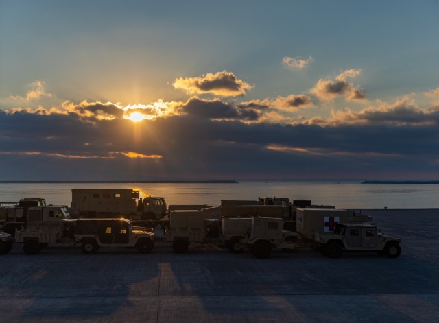 The sun rises over tactical vehicles belonging to 3rd Assault Helicopter “Nightmare” Battalion, 1st Aviation Regiment, 1st Combat Aviation Brigade, 1st Infantry Division, as they are staged awaiting transport by vessel at the port of Alexandroupoli, Greece, Nov. 22, 2021. The 1CAB will hand off its aviation mission in support of Atlantic Resolve to the 1st Air Cavalry Brigade out of Fort Hood, Texas.