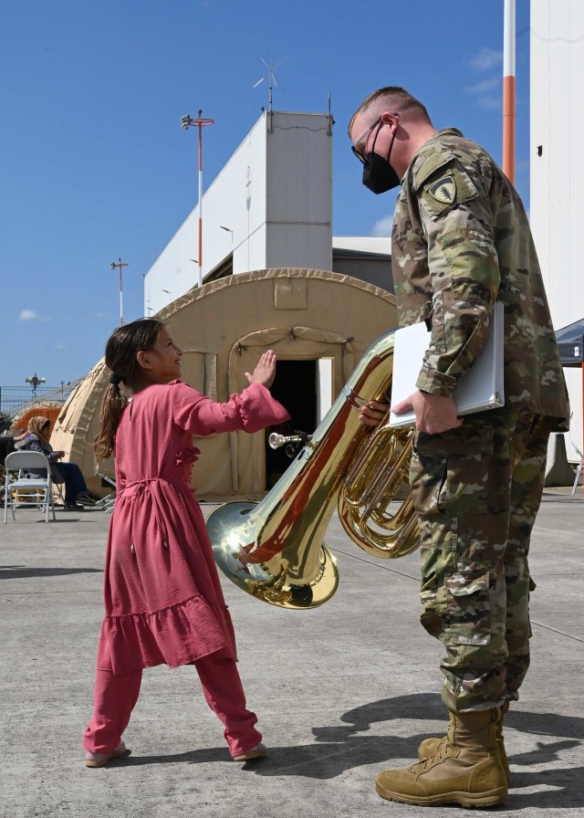 A U.S. Army Soldier with U.S. Army Europe and Africa Band and Chorus entertains an Afghan girl at Ramstein Air Base, Germany, Aug. 24, 2021. The USAEUR-AF Band & Chorus supported Operations Allies Welcome by providing entertainment to the evacuees while they are in temporary lodging at Ramstein Air Base. 