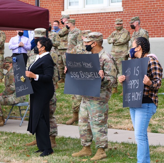 Soldiers and civilians of the 1st Theater Sustainment Command hold welcome home posters for the Soldiers redeploying from Camp Arifjan, Kuwait, Dec. 15, 2021 at Fort Knox, Kentucky. The 1st TSC is continuously deployed to the U.S. Central Command theater to provide mission command and execute anticipatory operational-level sustainment support to Army, joint, interagency and multinational forces in the U.S. Central Command area of responsibility. (U.S. Army photo by Spc. Kaylee Harris)