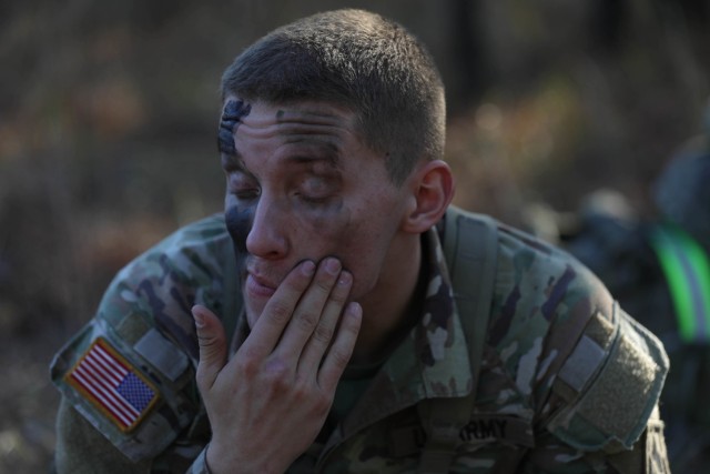 A soldier assigned to the 27th Engineer Battalion from the 20th Engineer Brigade applies face paint during the best squad competition on Dec. 15, 2021, on Fort Bragg North Carolina. The competition consisted of the Army Combat Fitness Test, a stress shoot, a star course designed to assess squads on squad-level tasks and drills to include reacting to a CBRN threat, conducting a hasty defence, movement a casualty to a medical site, reacting to contact, application of camouflage, and a mystery event dubbed brain games. (U.S. Army photo by Spc. Maxine Baen)