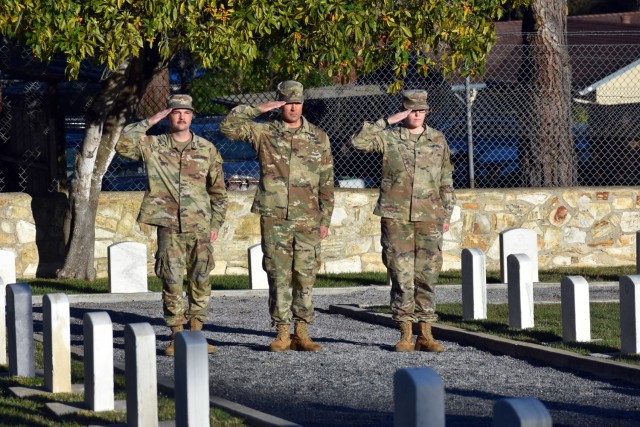 From left, Pvt. Joshua Bough, assigned to Company G, 229th Military Intelligence Battalion, Staff Sgt. Justin Sherman, assigned to Company D, 229 MI Bn., and Spc. Michaela Groh, assigned to Company C, 229th MI Bn., salute during a ceremony on...