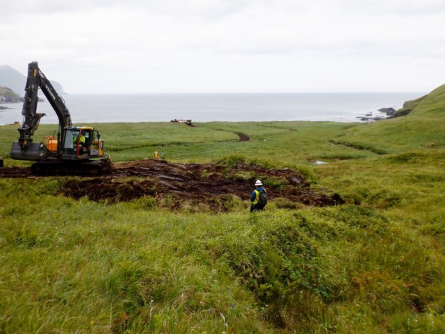 Crews work to recontour excavated areas to match the surrounding topography and replace the organic layer at the Cape Prominence Formerly Used Defense Site. Before the contaminated soil was removed, the field team carefully set aside and preserved...