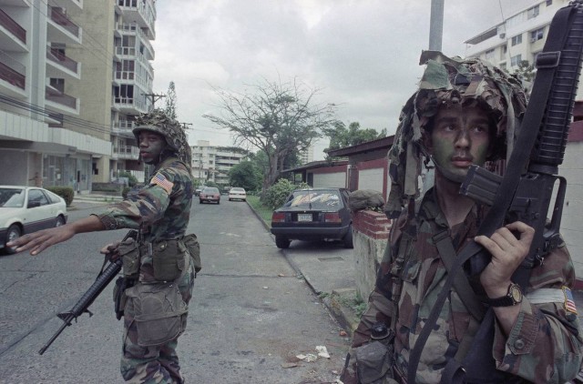 American soldiers direct traffic as they stand guard outside the residence of the Peruvian Ambassador, right rear, in Panama City, Tuesday, Jan. 9, 1990. 