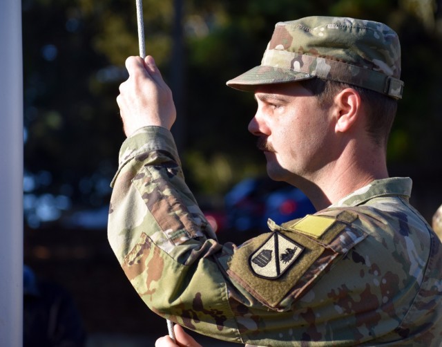 Pvt. Joshua Bough, assigned to Company G, 229th Military Intelligence Battalion, helps lower the flag to half-staff during a Wreaths Across America Ceremony at the Presidio of Monterey Cemetery, PoM, Calif., Dec. 18.