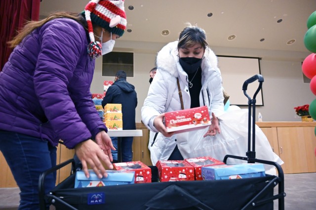 Contessa Ramos (right) places a box of cookies into a cart at the Four Chaplains Memorial Chapel prior to delivering them to staff duty locations on Camp Humphreys Dec. 20, 2021. (U.S. Army photo by Monica K. Guthrie)