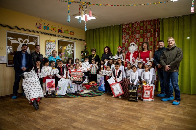U.S. Army soldiers and personnel stationed at Novo Selo Training Area, Bulgaria, pose for a group photo at a local school, Dec. 16, 2021. Novo Selo Training Area personnel were invited to local schools to share and share holiday traditions share and learn more about local culture. 