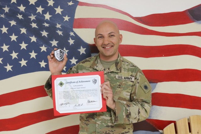 Sgt. Aqeel Ahmed poses for a photo with a Task Force Phoenix coin and a Certificate of Achievement he was awarded for his hard work while deployed to the Middle East.