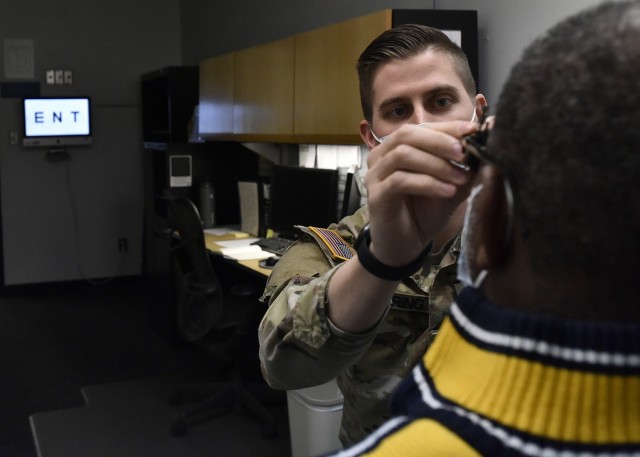 Capt. Michael Goering, a staff optometrist at General Leonard Wood Army Community Hospital’s Optometry Clinic, fits a telescopic device to a patient’s glasses to demonstrate one of the resources available to individuals diagnosed with low vision. 