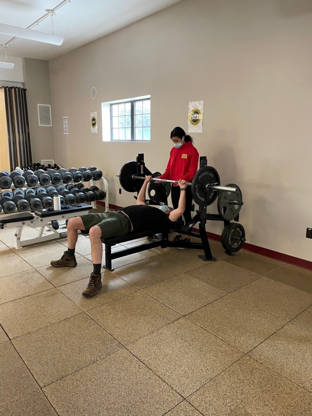 A female Natick personnel member spots another on the weight bench at the CPT James Burt Fitness Center located on Natick Soldier Systems Center, Natick, Mass. The fitness center is open for Soldiers and civilians who work on the installation. 