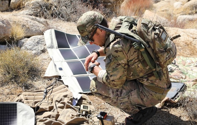 A U.S. Army Green Beret with 1st Special Forces Group (Airborne) sets up solar panels for operational communications at the National Training Center, Fort Irwin, California. The solar panels enable special operations forces to operate their equipment in the most remote locations and continue training forward of conventional forces while moving as a team through rough desert terrain, simulated ambushes and limited communications.