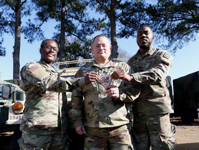 Spc. Daija Brunson, Sgt. 1st Class Jonathan Jones, and Spc. Christopher Williams hold a Shelby County Sheriff’s Office patch at the Millington National Guard Armory, Jan. 8. All three Soldiers are full-time deputies with the Shelby County...