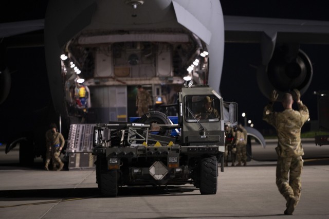 U.S. Air Force Airman 1st Class Chase Smith, right, 8th Airlift Squadron loadmaster, marshals a K-loader toward a C-17 Globemaster III, assigned to Joint Base Lewis-McChord, Washington, at Travis Air Force Base, California, Feb. 14, 2022. U.S. Airmen with the 60th Aerial Port Squadron and 8th Airlift Squadron load K-loaders onto the C-17. K-loaders are used to transport cargo into and out of aircraft. Under the direction of U.S. Transportation Command, the 60th Air Mobility Wing supported the 621st Contingency Response Wing during the movement of security assistance cargo to Ukraine via commercial cargo aircraft. The Defense Security Cooperation Agency coordinated the effort. (U.S. Air Force photo by Senior Airman Karla Parra)