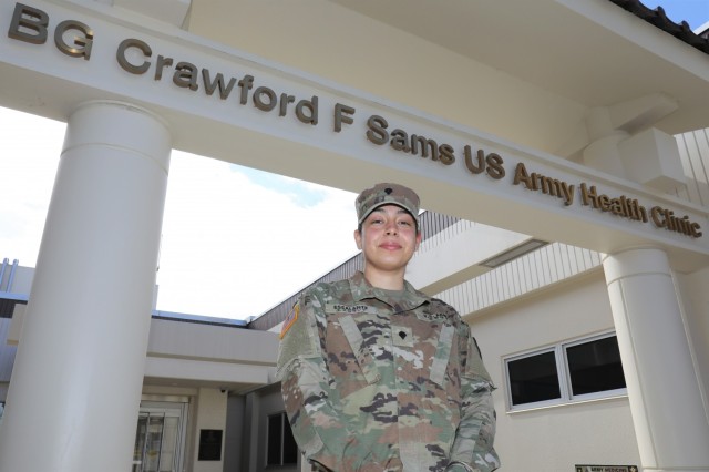 SPC.  Antonella Escalante, a lab technician assigned to U.S. Army Medical Department Activity Japan, stands outside the U.S. Army BG Sams Health Clinic at Camp Zama, Feb. 24, 2022. Escalante credits her family for instilling in her the values ​​she tries to live by.  in his work and volunteering.