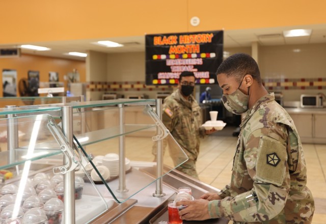 On February 28, 2022, soldiers fill the tray at the Cantiny Dining Facility for a Black History Month meal designed to serve both cultural and nutrition-focused food.