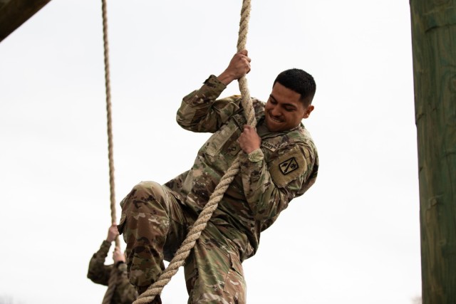 Pfc. Mario Delahoya, a member of 45th Field Artillery Brigade, Oklahoma Army National Guard, climbs a rope during the obstacle course event of the Best Warrior Competition at Camp Gruber Training Center, Oklahoma, March 5, 2022. The three-day...