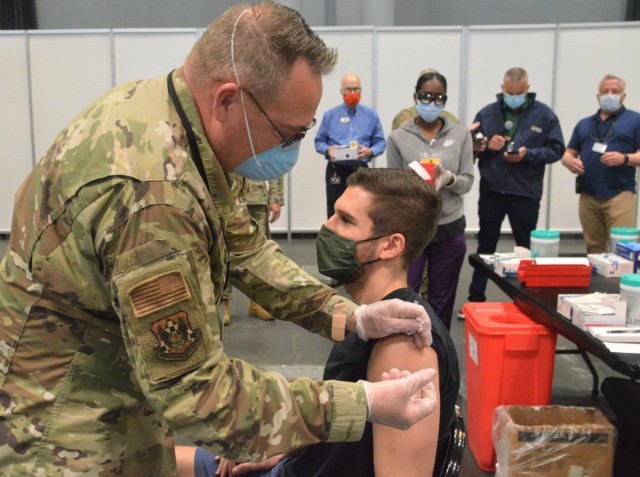 Air Force Lt. Col. John Reynolds, a member of the New York Air National Guard's 105th Airlift Wing, vaccinates Tom Pescatore May 20, 2021 at the Jacob Javits Convention Center in New York City. Pescatore's injection was the 600,000 shot...