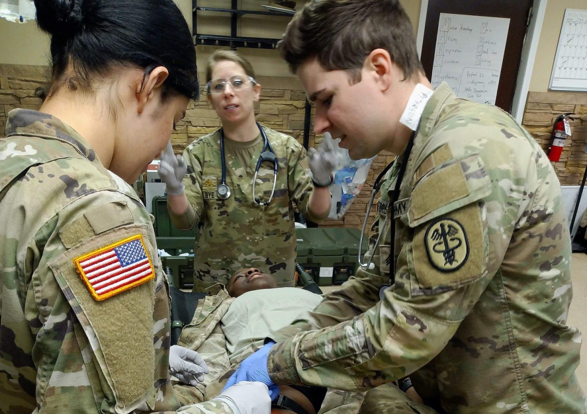 Maj. Colleen Bye works with medics Spc. Jennifer Membreno and Sgt. Weslyn Peterson to re-secure a tourniquet for a simulated gunshot wound to the leg during the field training exercise at the gun range at Fort Lee, Virginia. (U.S. Army photo by Spc. Takaila Warfield)