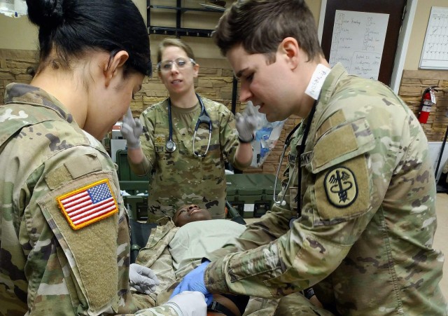 Maj. Colleen Bye works with medics Spc. Jennifer Membreno and Sgt. Weslyn Peterson to re-secure a tourniquet for a simulated gunshot wound to the leg during the field training exercise at the gun range at Fort Lee, Virginia.