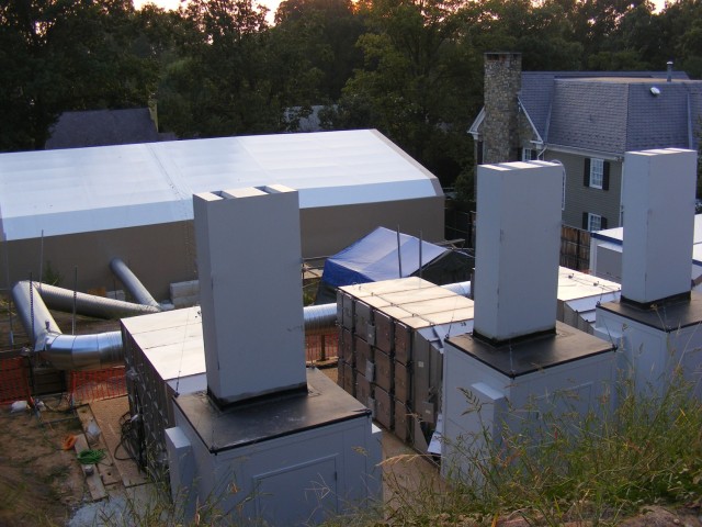 An evening view of the site during remedial activities that highlights the three large chemical agent filters connected to the containment tent by ductwork.  These filters were adapted for use at this site with sound suppression structures so that their large electric motors would not disturb the neighborhood after hours.
