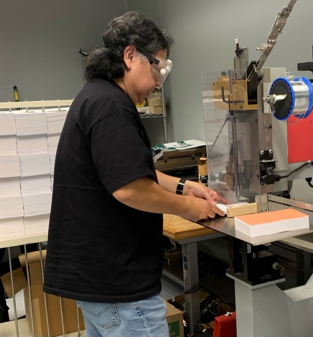 Defense Logistics Agency Document Services employee Sam Onofre uses a Deluxe M30 to wire stitch a book while working at a DLA print facility in North Island, California, March 10, 2022.