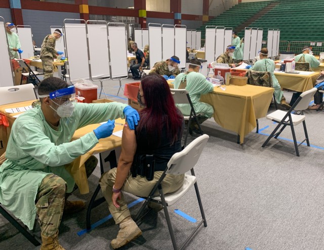 Spc. Joshua Mercado, a medic from Joint Task Force - Puerto Rico applies a COVID-19 vaccine at the Coliseíto Pedrín Zorrilla in San Juan, Puerto Rico, Jan. 13, 2021. The Puerto Rico National Guard remains committed to provide the COVID-19 vaccines to healthcare professionals and first responders as part of Operation Warp Speed. (U.S. Army National Guard photo by Spc. Kevin Torres)