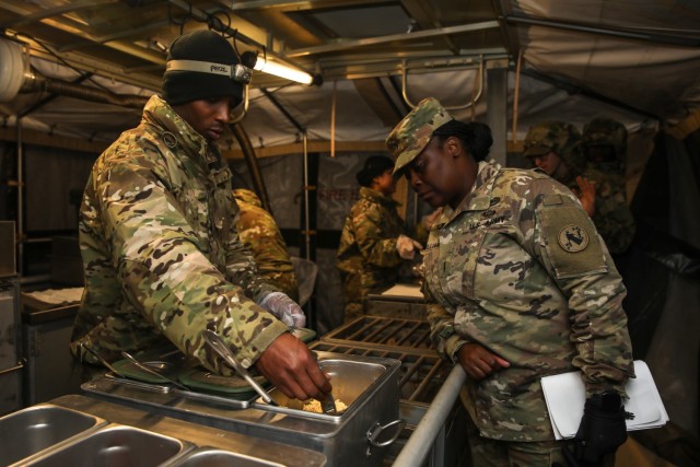 U.S. Army Pfc. Avery Barnes (left), a culinary specialist assigned to 511th Quartermaster Company, 1st Special Troops Battalion, 1st Sustainment Brigade, 1st Infantry Division, takes the temperature of the breakfast being served at the 54th Annual...