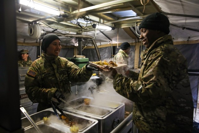 U.S. Army Sgt. Maria Anaya (left), a culinary specialist for 511th Quartermaster Company, 1st Special Troops Battalion, 1st Sustainment Brigade, 1st Infantry Division, serves lunch to U.S. Army Pfc. Avery Barnes (right), another member of the 511 QMC field-feeding team, during the 54th Annual Philip A. Connelly Awards Program culinary competition March 22nd, 2022, at Fort Riley, Kansas.