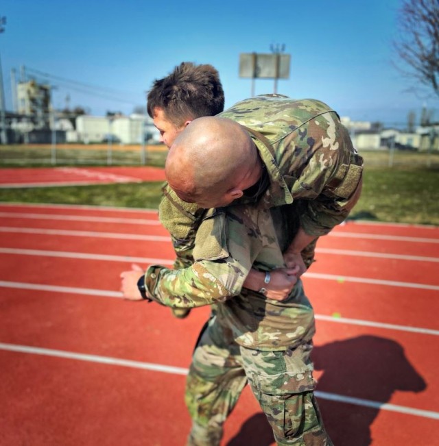 During a mock triathlon at Caserma Ederle in Vicenza, Italy, 1st Lt. Benjamin Pritchett runs with Sgt. 1st Class Junior Reyes in the classic buddy carry, their final task of the training on March 8, 2022 at Caserma Ederle in Vicenza, Italy.