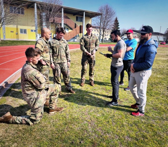 Josh Grant, right, a tactical strength and conditioning coach from the U.S. Army Garrison Italy’s Directorate of Family, Morale Welfare and Recreation, and fellow coaches discuss performance during a mock triathlon for paratroopers preparing for Army competitions at Caserma Ederle in Vicenza, Italy on March 8, 2022. 