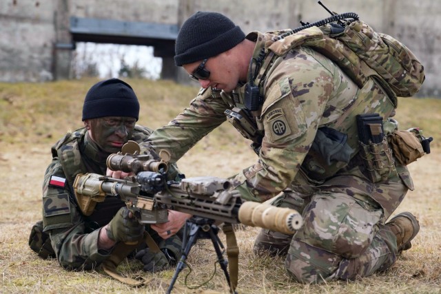 A paratrooper with the 3rd Brigade Combat Team, 82nd Airborne Division, introduces a Polish soldier to an M110A1 squad designated marksman rifle during a training event in Zamość, Poland, Feb. 28, 2022.