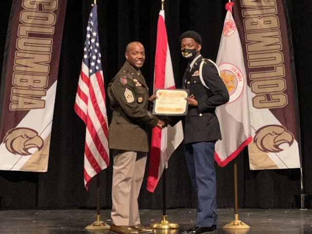 (From left) U.S. Army Security Assistance Command (USASAC) Command Sgt. Major Sean J. Rice presents a Leadership Excellence award certificate to JROTC Cadet and Alpha Company Commander Capt. Jordan Anglin (pictured) and Cadet Sgt. Maj. Jayquan Barber (not pictured) , S-3 Operations sergeant major, during the Columbia High School&#39;s 15th Annual Eagle Battalion JRTOC Awards Ceremony March 22, 2022 in Huntsville, Alabama. Rice attended the ceremony and recognized the cadets on behalf of the USASAC commanding general, Brig. Gen. Garrick Harmon. For more information about the Columbia High School JROTC, visit https://www.huntsvillecityschools.org/schools/columbia-high-school/jrotc-0. For more information about USASAC and its vital foreign policy mission, visit www.army.mil/usasac.
