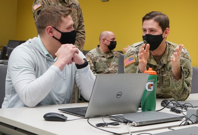Capt. Sean Smith, right, deputy cyber chief for the Defensive Cyber Operations Element, talks with a student during the Pennsylvania National Guard Wi-Fighter Cyber Challenge at Penn State University March 16, 2022. (U.S. Army by Sgt. 1st Class Matthew Keeler).