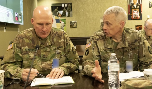 Master Sgt. Brian Atkinson (left) and Chaplain (Col.) Mike Crawford, both of the Iowa Army National Guard, review their notes during the First Army Command Chaplain Symposium in the Pershing Conference Room of First Army headquarters on Rock Island Arsenal, Ill. 