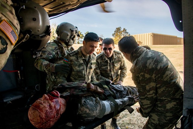 An Oklahoma Army National Guard UH-60 Black Hawk helicopter crew member uses a rescue winch to load a patient from the ground onto the helicopter during a medical knowledge exchange with military doctors with the Azerbaijan Operation Capabilities Concept Battalion in Oklahoma City, April 1, 2022. Oklahoma City. The knowledge exchange involved the participation and support of Guardsmen with both the Oklahoma Army and Air National Guard in support of the State Partnership Program. 