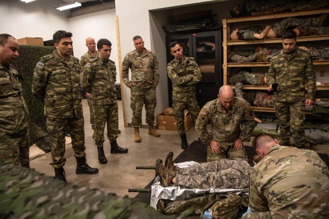 U.S. Army Sgt. Matthew Smith, right, and U.S. Army Sgt. 1st Class Chris Dent, both combat medic instructors at the Oklahoma National Guard Regional Training Institute, demonstrate a casualty care scenario to doctors with the Azerbaijan Operational Capabilities Concept Battalion during a medical knowledge exchange event at the RTI in Oklahoma City, March 30, 2022. The knowledge exchange involved the participation and support of Guardsmen with both the Oklahoma Army and Air National Guard in support of the State Partnership Program.