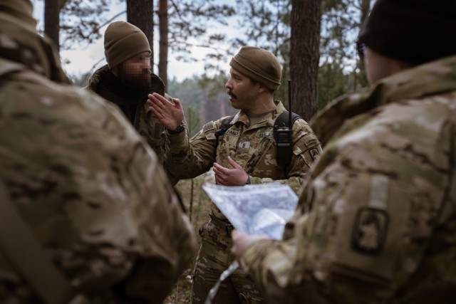 Chief Warrant Officer 2 Dominic Constance, a UH-60 Blackhawk helicopter from the 1-214th General Support Aviation Battalion, 12th Combat Aviation Brigade talks with a Polish Armed Forces reconnaissance soldier during a personnel recovery exercise at the Nowa Deba Training Area, Poland, April 4, 2022. This exercise and others like it enhances our interoperability with our NATO allies and partners strengthens the regional relationships that we have developed. 12 CAB is the only enduring aviation brigade present throughout Europe that enables us to deter and defend against threats from any direction. (U.S. Army photo by Staff Sgt. Thomas Mort)