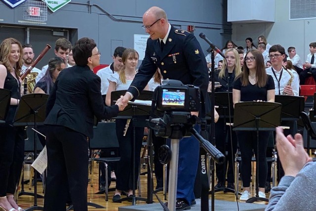 Spc. Douglas Olenik, a tuba player with the 399th Army Band and leader of its Route 66 Brass Band, shakes hands with his very first band director, Diana Kobs, after a performance he conducted March 30 at his alma mater, Norwayne High School, in Creston, Ohio.