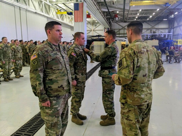 Ohio Army National Guard Brig. Gen. Stephen Rhoades, center, commander of Special Troops Command (Provisional), pins the Purple Heart on Sgt. Tristan Meyers April 10, 2022, during a ceremony at the Army Aviation Support Facility #1 in North...
