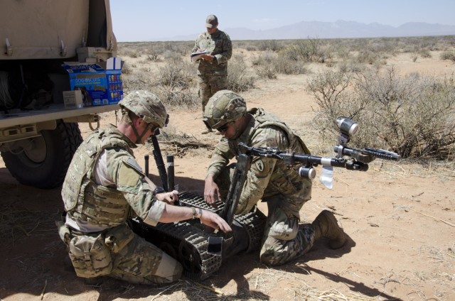 EOD Technicans Spc. Andrew Webb (right) and Staff Sgt. John Bradshaw (left) prepare a robot to investigate a simulated bomb in a trainnig event while Observer/Controller Sgt. 1st Class John Mullie (back) documents thier performance in the training event.
