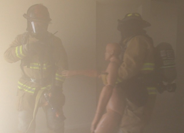 Firefighters at Fort Huachuca, Ariz. pull a simulated victim from a house here as part of training on how to respond to and extinguish structure fires.