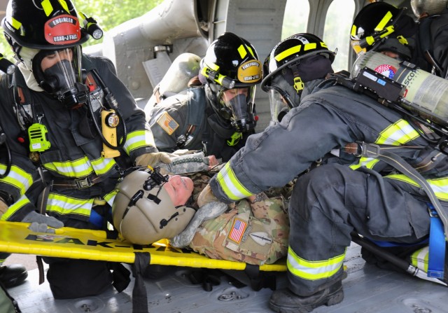 Firefighters from the U.S. Army Garrison Japan Fire Department evacuate Chief Warrant Officer 4 Joseph Mattos during a mock aircraft crash at Kastner Airfield, Camp Zama, Japan, April 28, 2022. Mattos, the aviation maintenance officer for U.S. Army Aviation Battalion Japan, was one of the pilots of a UH-60 Black Hawk helicopter that simulated a crash landing.