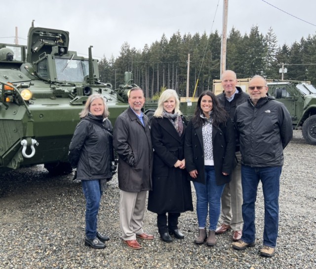 Olympia Community Connectors (R-L) Sam Gibboney, Port of Olympia Executive Director; City Manager Jay Burney; Mayor Cheryl Selby; Jennie Foglia-Jones, Marketing and Communications, Port of Olympia; Tom Jameson, JBLM Military Liaison; and Bob Iyall, Commissioner, Port of Olympia pose for a photo just after taking a ride in one of Ghost Brigade&#39;s new Strykers. 