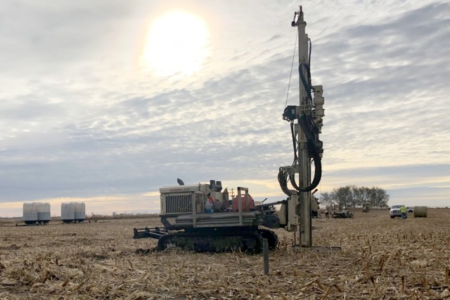 Drill rig is positioned to install drill rods at the next location for amendment injections. Two drill rods already installed are visible in front of the rig. Holding tanks filled with amendment for injections are staged in the background.