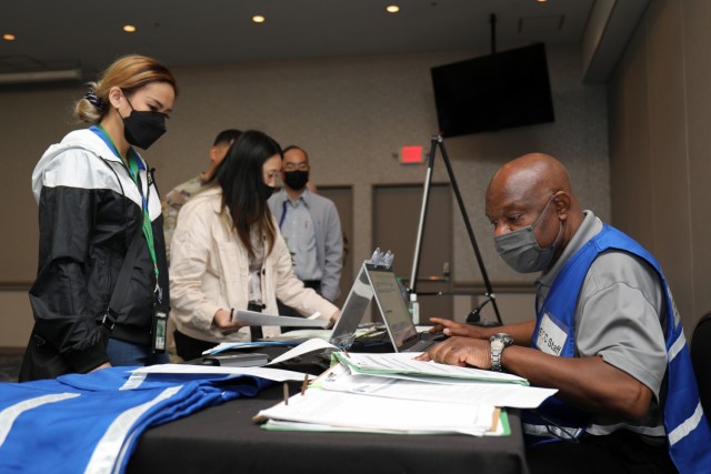Cedric Davis, right, chief of postal operations at Camp Zama, Japan, fills out travel orders for Christina Henson during an Emergency Evacuation Program drill inside the Camp Zama Community Club May 9, 2022.