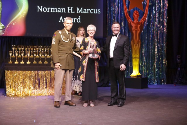 Event emcee Vikki Hanrahan was surprised by an alternate script naming her as the recipient of the 2022 IMCOM Norman H. Marcus Award for unprecedented contributions to FMWR programs in Europe. Hanrahan is the entertainment director for USAG Ansbach&#39;s Terrace Playhouse. 