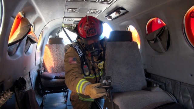 A firefighter at Fort Huachuca, Ariz. checks for dangerous gasses inside an airplane during training on how to respond to an aircraft accident at Libby Army Airfield.
